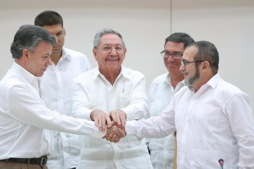 Cuba's President Raul Castro (C) stands as Colombia's President Juan Manuel Santos (L) and FARC rebel leader Rodrigo Londono, better known by the nom de guerre Timochenko, shake hands in Havana, September 23, 2015. Colombian President Juan Manuel Santos and the top commander of leftist FARC rebels shook hands on Wednesday and agreed to reach a final peace agreement within six months in Latin America's longest war. "The chief of the FARC secretariat and I have agreed that in no more than six months this negotiation should come to an end and we should sign a final agreement," Santos told a ceremony in Havana, the site of peace talks for the past three years. REUTERS/Alexandre Meneghini       TPX IMAGES OF THE DAY
