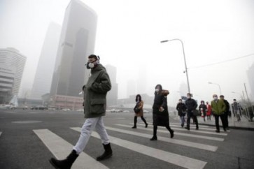 مارة يرتدون كمامات للحماية من تلوث الهواء في بكين