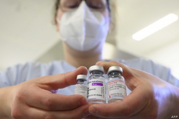A woman wearing a face mask shows three vials with different vaccines against Covid-19 by (L-R) Pfizer-BioNTech, AstraZeneca and Moderna in the pharmacy of the vaccination center at the Robert Bosch hospital in Stuttgart, southern Germany, on February 12, 2021, amid the novel coronavirus / COVID-19 pandemic. (Photo by THOMAS KIENZLE / AFP)